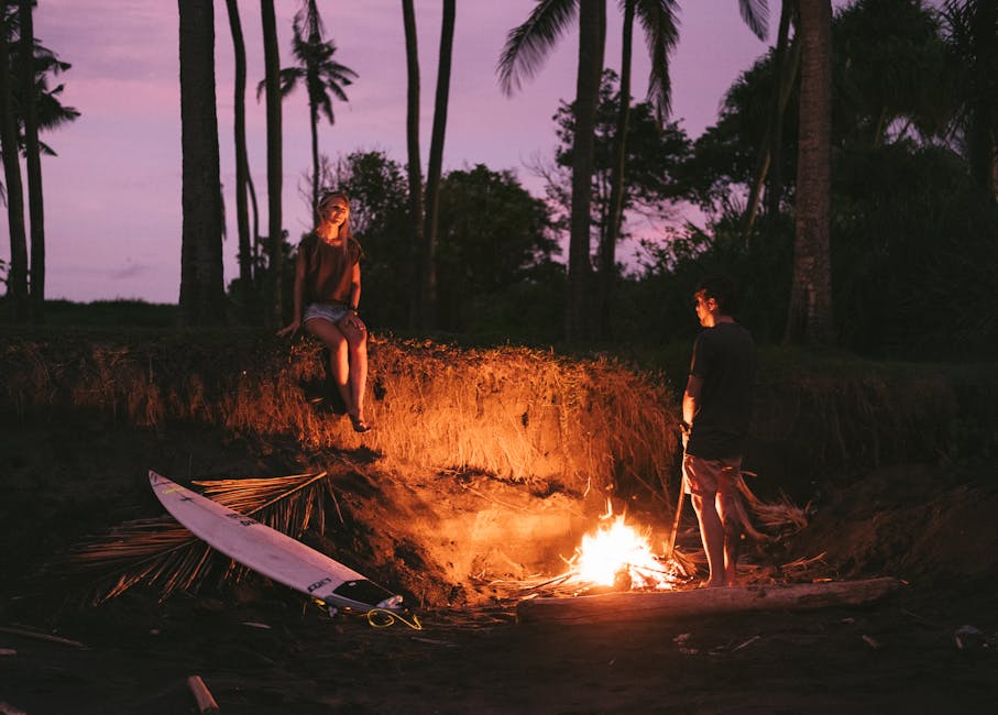 Romantic couple having date on beach near bonfire during sundown